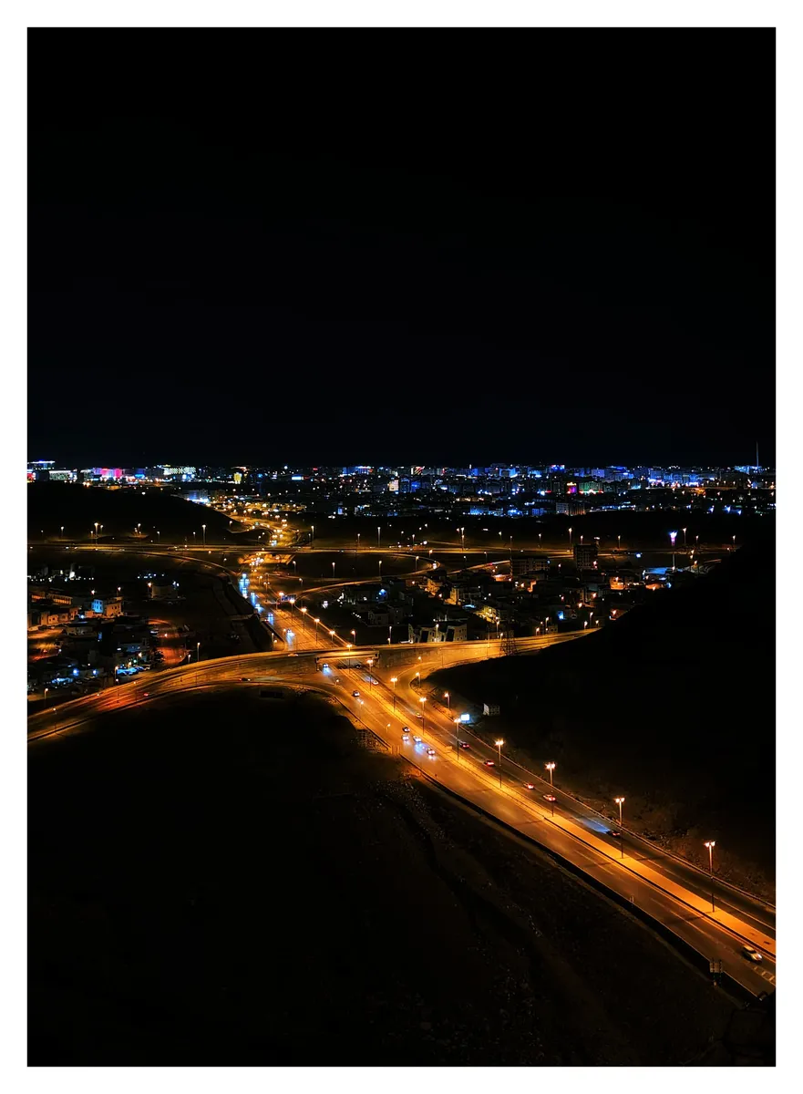 Highways lit orange winding into a city at night